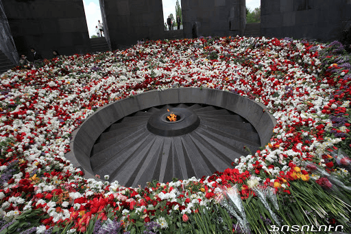 Vista amplia del espacio interior del memorial Tsitsernakaberd en Ereván, llama perpetua rodeada de flores.