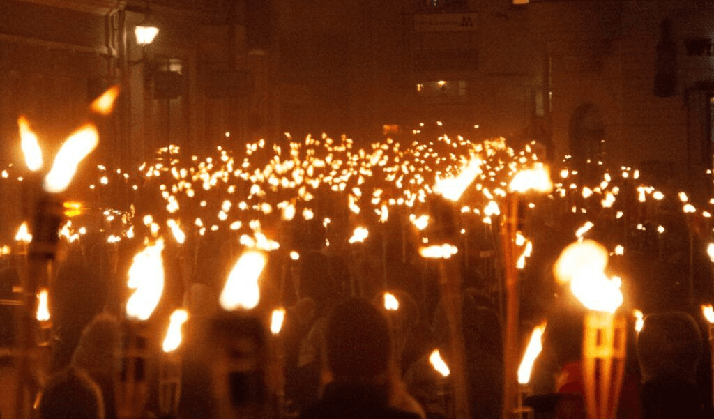 Multitud en la Marcha de Antorchas nocturna en Ereván, faroles y luz cálida entre edificios.