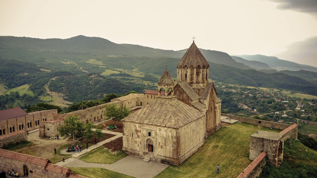 Vista aérea del monasterio de Gandzasar en un monte arbolado: iglesia central con cúpula facetada, gavit con tejado a dos aguas, murallas.
