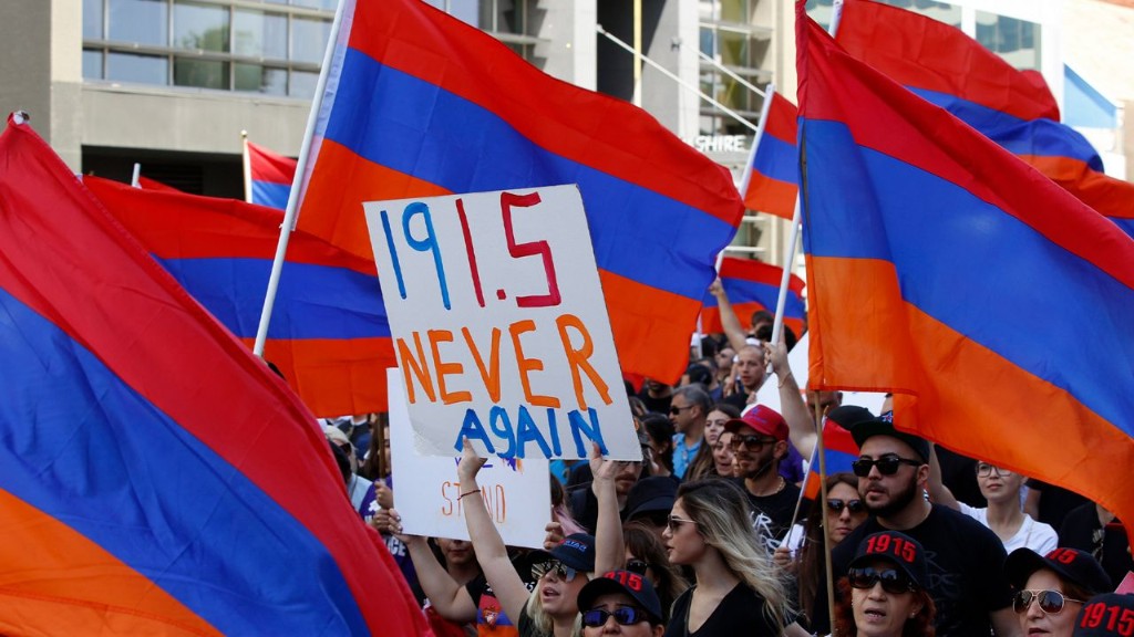 Manifestantes con banderas armenias; cartel central con letras 1915 Never Again en colores rojo, azul y naranja.
